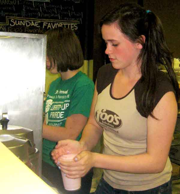 Maggie Bowen, right and co-worker Claire Odegard work to get an ice cream order of a concrete mix together. While Maggie places a lid on top of the ice cream Odegard prepares another order that was taken. (Mady Sargent)