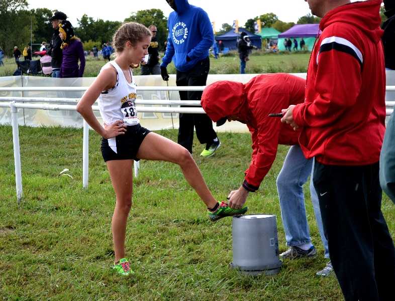 Junior Ann Campbell waits for the time chip to be removed from her shoe after the race. Campbell finished first in the KC Metro Cross Country Championship Oct. 5 with a time of 18 minutes 44 seconds. Photo by Hannah Bredar.