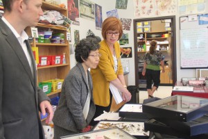 STA president Nan Bone shows visitors Anthony Hollinghurst, left, and Sister Grace Saito the biology project for which students must collect insects and pin them in a display case.